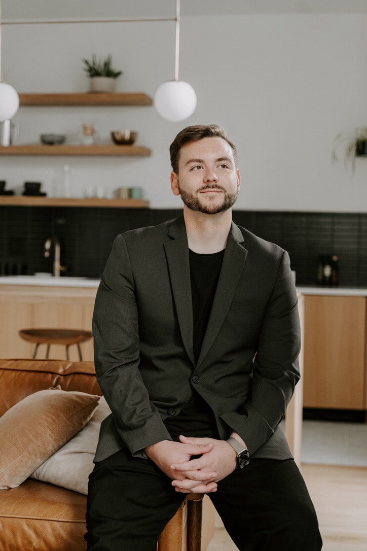 Erick Dronski seated in a black blazer in a bright studio